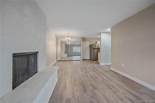 unfurnished living room with light hardwood / wood-style floors and a brick fireplace