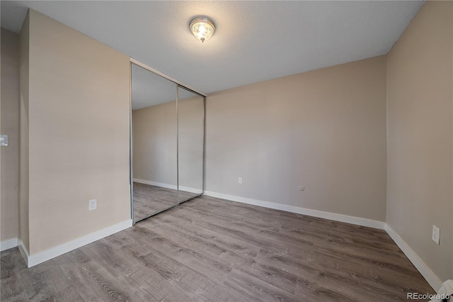 unfurnished bedroom with hardwood / wood-style floors, a textured ceiling, and a closet