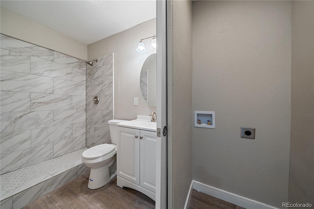 bathroom with tiled shower, vanity, hardwood / wood-style flooring, and toilet