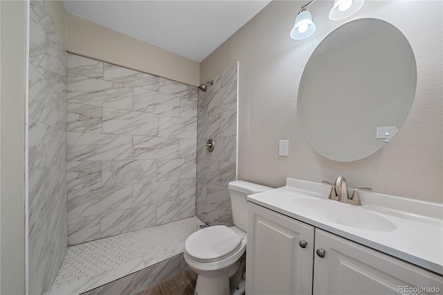 full bath with toilet, vanity, and tiled shower