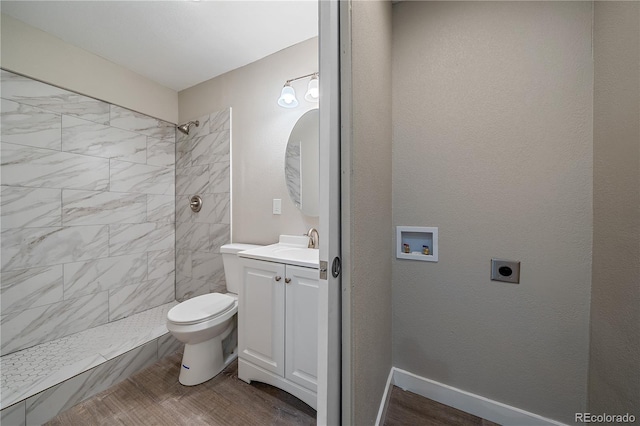 full bathroom featuring toilet, wood finished floors, vanity, and tiled shower