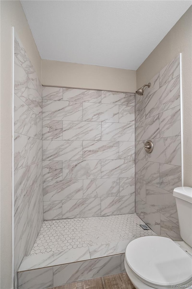 full bathroom featuring a tile shower and toilet