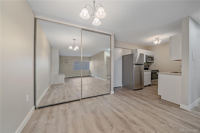 interior space with a baseboard radiator, light wood-style flooring, an inviting chandelier, stainless steel appliances, and light countertops