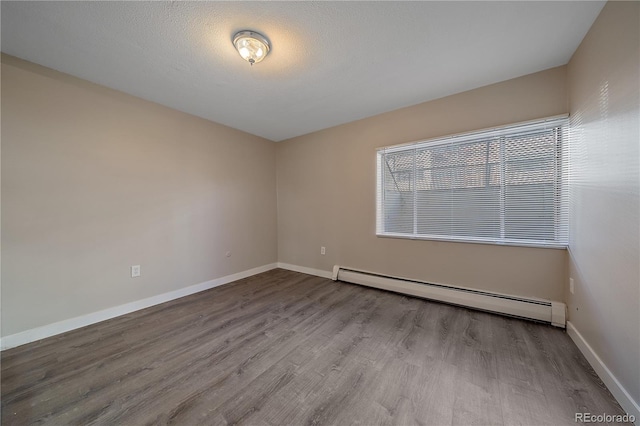 unfurnished room featuring baseboards, wood finished floors, and a baseboard radiator