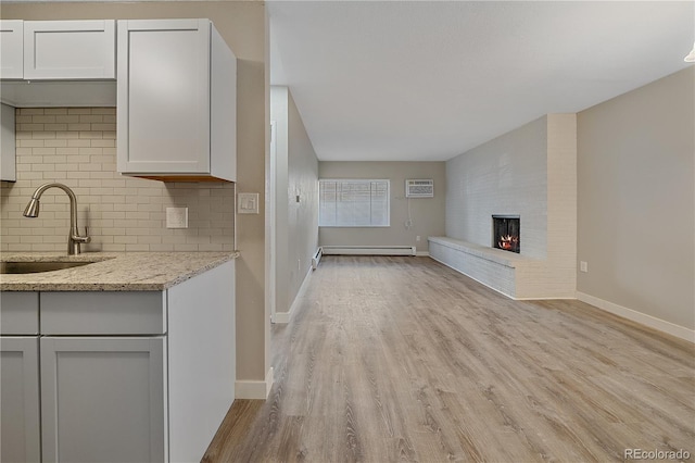 4110 Hale Pkwy Unit 1E, Denver, CO 80220 - unfurnished living room with a sink, light wood-style floors, a brick fireplace, a wall unit AC, and baseboards