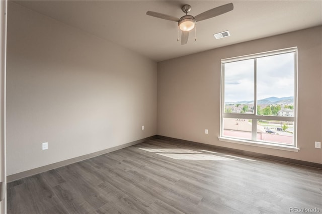 empty room featuring hardwood / wood-style flooring, ceiling fan, and a mountain view