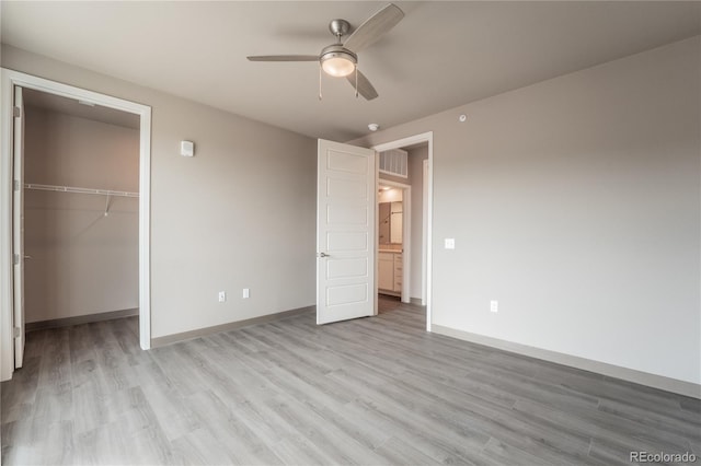 unfurnished bedroom with ceiling fan, a closet, light hardwood / wood-style flooring, and a walk in closet