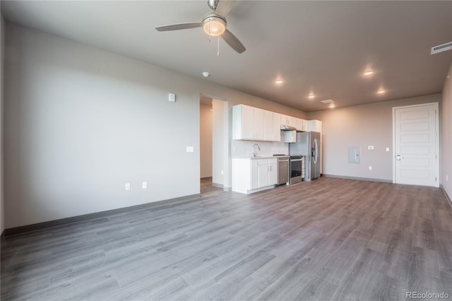 unfurnished living room featuring ceiling fan, sink, and light wood-type flooring