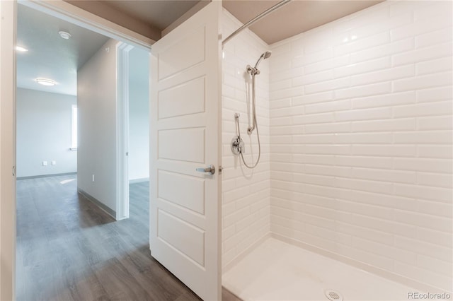 bathroom with hardwood / wood-style floors and a tile shower