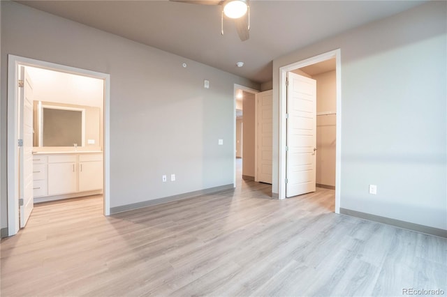 unfurnished bedroom with ensuite bath, a spacious closet, a closet, ceiling fan, and light hardwood / wood-style floors