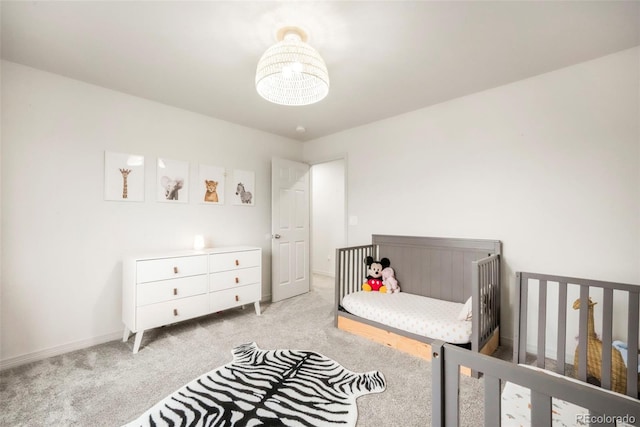 2204 Reed Grass Way, Colorado Springs, CO 80915 - bedroom with light colored carpet, a nursery area, baseboards, and a chandelier
