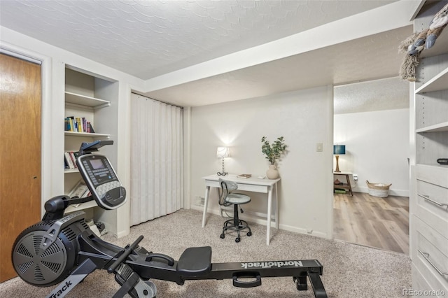 exercise room featuring light carpet and a textured ceiling