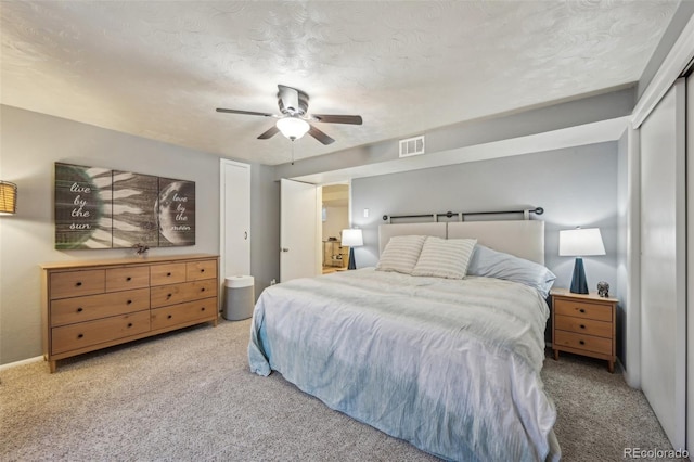 carpeted bedroom with ceiling fan and a textured ceiling