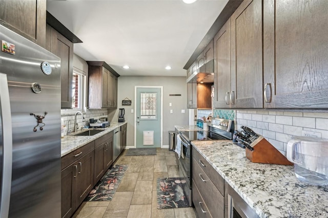 kitchen with sink, backsplash, light stone counters, dark brown cabinetry, and stainless steel appliances