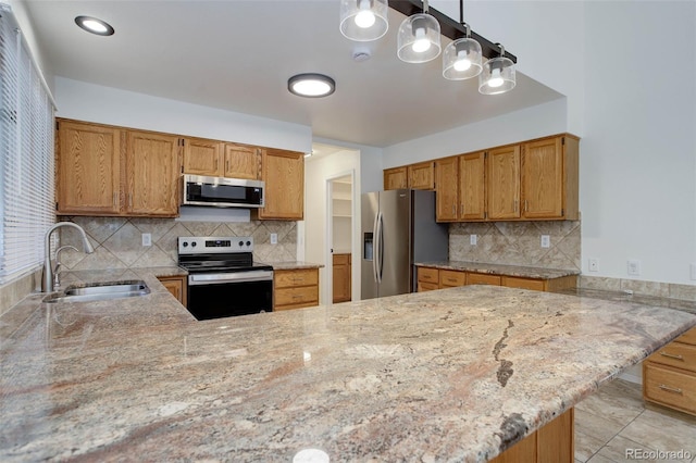 6055 W Warren, Lakewood, CO 80227 - kitchen with appliances with stainless steel finishes, a peninsula, tasteful backsplash, and light stone counters