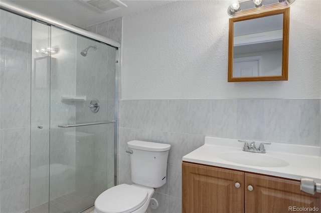 6055 W Warren, Lakewood, CO 80227 - bathroom with a shower stall, vanity, tile walls, and a wainscoted wall