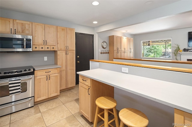 745 S Glencoe St, Denver, CO 80246 - kitchen with appliances with stainless steel finishes, light brown cabinets, a breakfast bar area, recessed lighting, and light tile patterned flooring