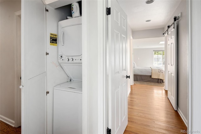 745 S Glencoe St, Denver, CO 80246 - washroom with estacked washer and dryer, light wood-type flooring, and a barn door