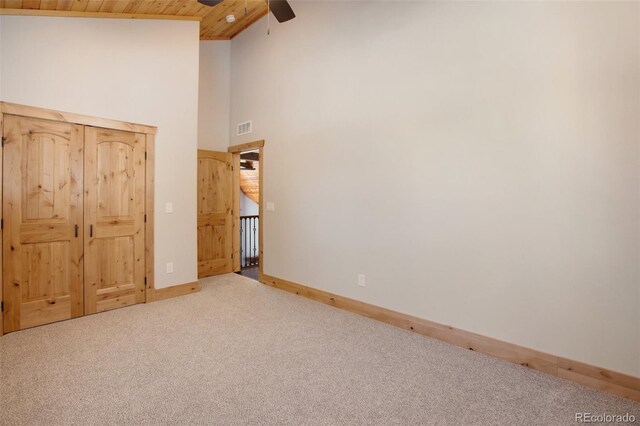 unfurnished bedroom featuring carpet flooring, ceiling fan, wooden ceiling, and high vaulted ceiling