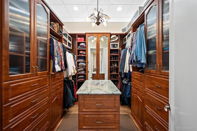 walk in closet featuring a paneled ceiling and an inviting chandelier