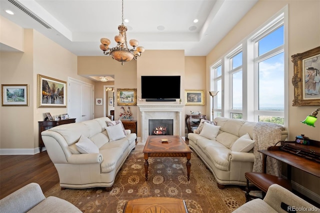 living room with dark wood-style floors, a tray ceiling, baseboards, and a premium fireplace