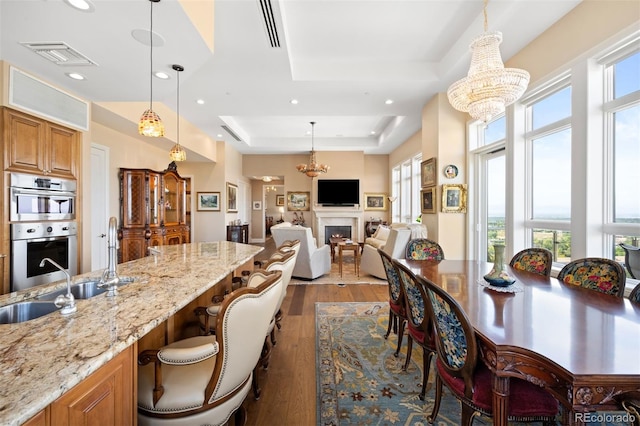 kitchen featuring double oven, a breakfast bar area, visible vents, light stone countertops, and a tray ceiling