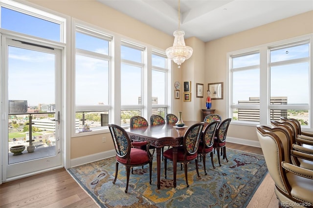 dining room with light wood finished floors, baseboards, and an inviting chandelier