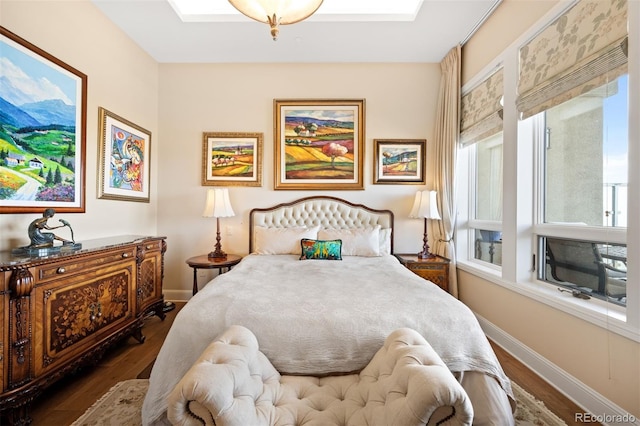 bedroom featuring dark wood-style floors, a skylight, and baseboards