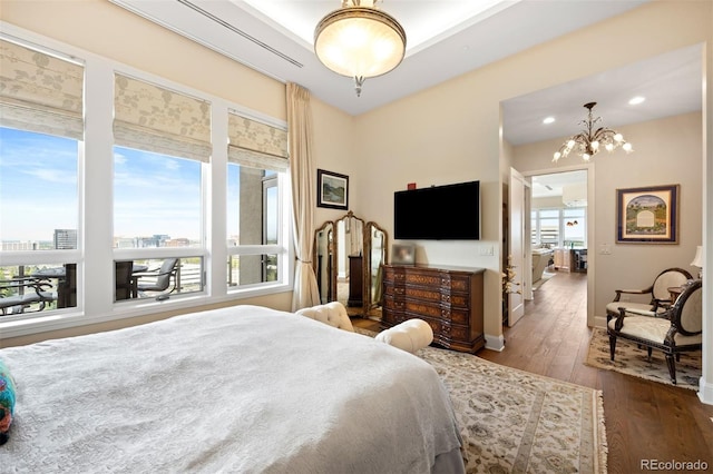 bedroom featuring a view of city, multiple windows, a notable chandelier, and wood finished floors