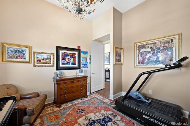 interior space with a notable chandelier, wood finished floors, a towering ceiling, and baseboards