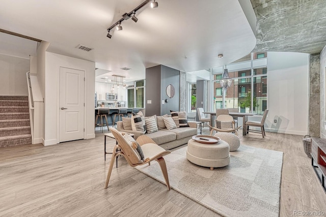 1700 Bassett St Unit 101, Denver, CO 80202 - living room featuring a chandelier, track lighting, light wood-type flooring, stairs, and baseboards