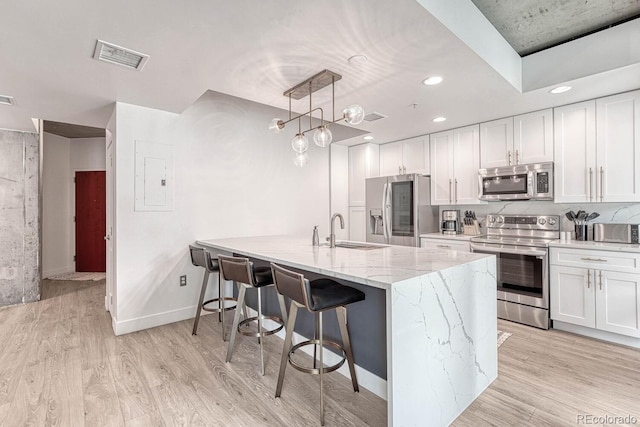 1700 Bassett St Unit 101, Denver, CO 80202 - kitchen featuring appliances with stainless steel finishes, a sink, a breakfast bar area, a peninsula, and white cabinetry