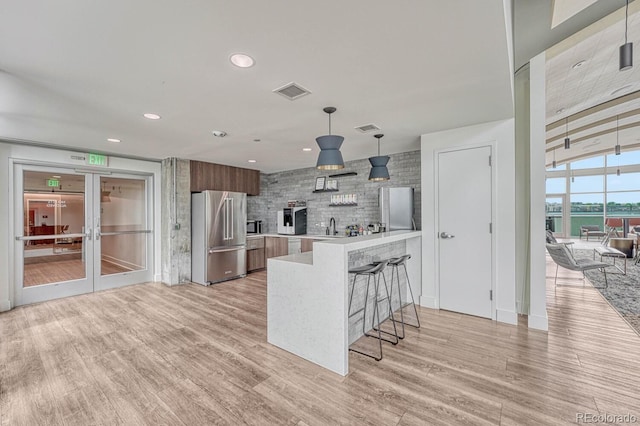 1700 Bassett St Unit 101, Denver, CO 80202 - kitchen with high quality fridge, light countertops, modern cabinets, light wood finished floors, and a breakfast bar
