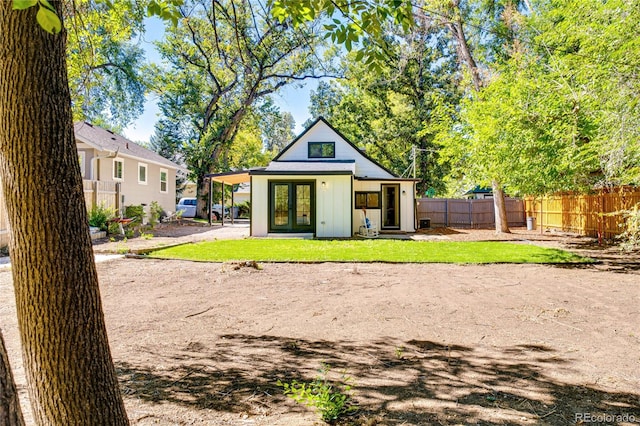 rear view of house with french doors and a lawn