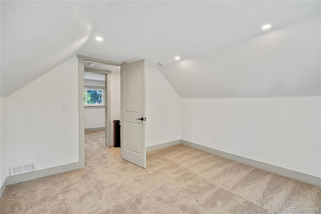 bonus room with lofted ceiling and light colored carpet