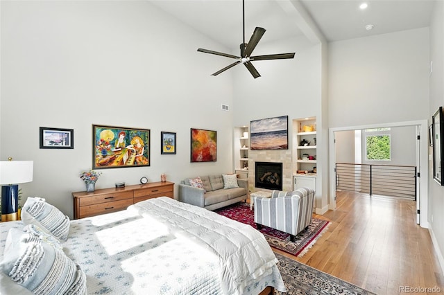 2635 Pierce St, Wheat Ridge, CO 80214 - bedroom featuring high vaulted ceiling, wood finished floors, a tiled fireplace, and ceiling fan