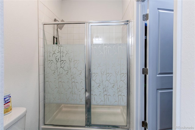 bathroom with a shower with door and toilet