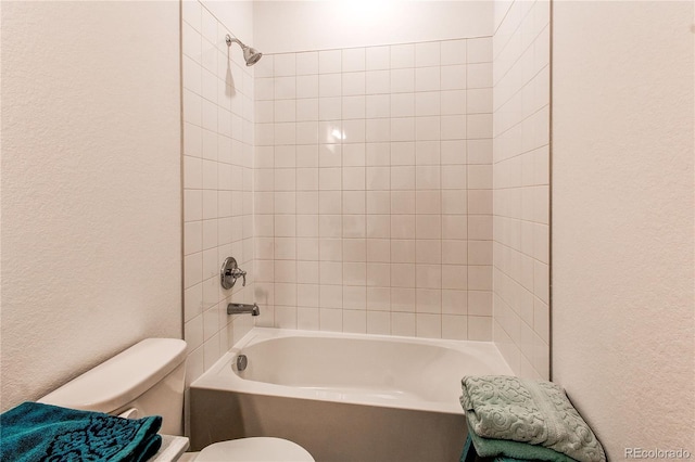 bathroom featuring tiled shower / bath and toilet