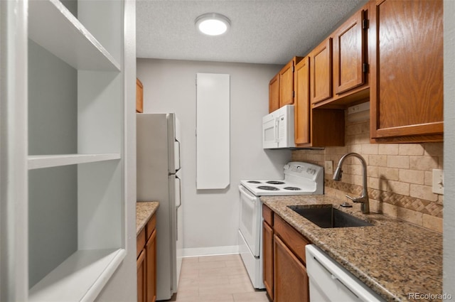 kitchen with white appliances, a textured ceiling, light stone counters, and tasteful backsplash