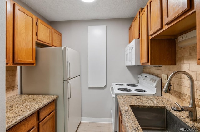 kitchen featuring decorative backsplash, white appliances, light stone countertops, a textured ceiling, and sink