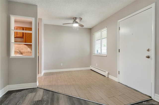 interior space featuring ceiling fan, hardwood / wood-style flooring, baseboard heating, and a textured ceiling