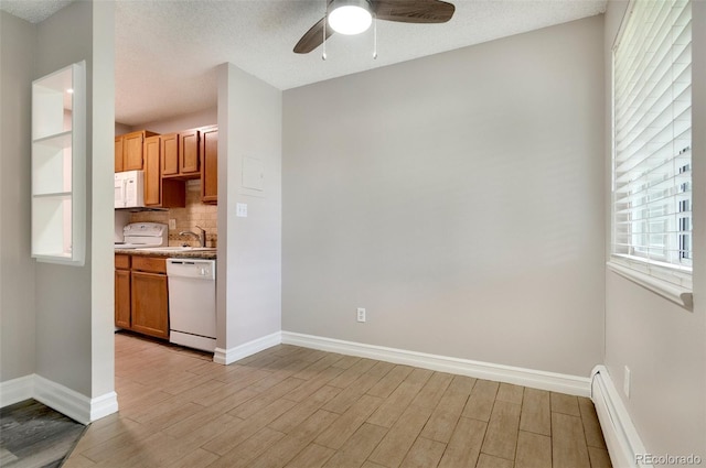 kitchen featuring a baseboard heating unit, white appliances, ceiling fan, and a wealth of natural light