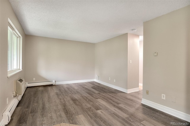 empty room with a textured ceiling, baseboard heating, and hardwood / wood-style flooring