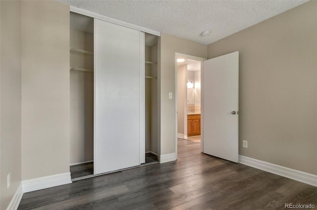 unfurnished bedroom featuring a textured ceiling, dark hardwood / wood-style flooring, and a closet