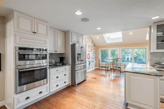7750 S Glencoe Way, Centennial, CO 80122 - kitchen featuring appliances with stainless steel finishes, a skylight, stone counters, tasteful backsplash, and light wood-type flooring