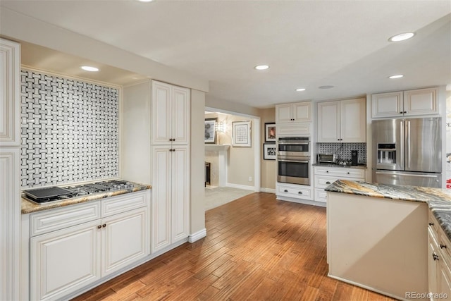 7750 S Glencoe Way, Centennial, CO 80122 - kitchen with stainless steel appliances, decorative backsplash, recessed lighting, light wood-style flooring, and light stone countertops