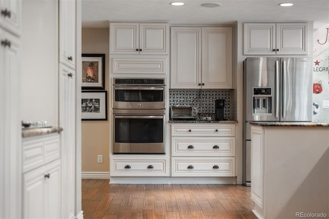 7750 S Glencoe Way, Centennial, CO 80122 - kitchen featuring stainless steel appliances, wood finished floors, dark stone counters, tasteful backsplash, and recessed lighting