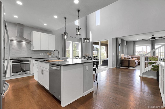 4781 Basalt Ridge Cir, Castle Rock, CO 80108 - kitchen featuring appliances with stainless steel finishes, wall chimney range hood, dark countertops, a sink, and open floor plan