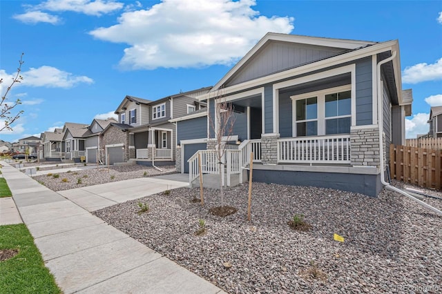 13392 E 110th Way, Commerce City, CO 80022 - view of front of house featuring covered porch, a residential view, stone siding, fence, and driveway