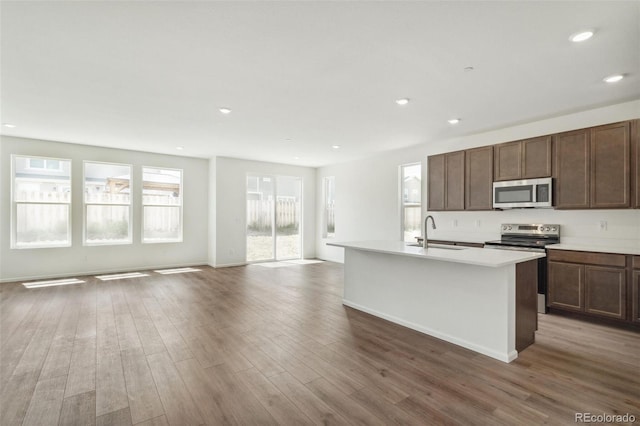 13392 E 110th Way, Commerce City, CO 80022 - kitchen with stainless steel appliances, open floor plan, an island with sink, wood finished floors, and a sink